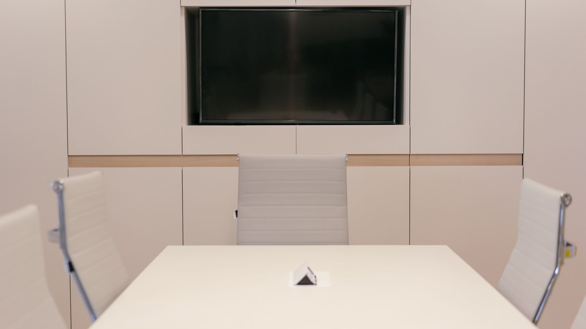 Conference room setup — meeting room with a wall-mounted display and white chairs